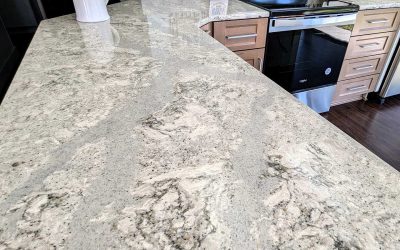 Close-up of a kitchen with light grey granite countertops featuring intricate patterns. Wooden cabinets and stainless steel appliances are visible in the background, adding a modern touch to the space.